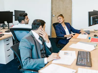 Colleagues working at desks with paperwork in an Indian office